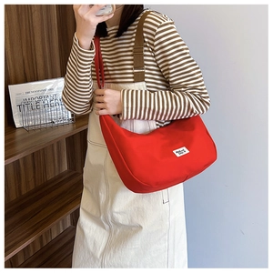 Detailed close-up of a red canvas crescent bag with branded patch and nylon strap