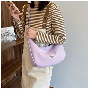 Detail view of light purple crescent nylon bag with white tag on a casual shoulder strap