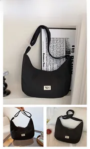 Detail of black nylon hobo bag with adjustable strap and minimalist white woven label