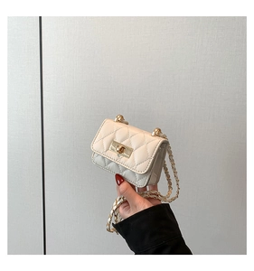 Macro shot of white quilted mini bag with gold twist lock and woven chain strap detail