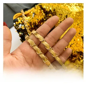 Detail of gold metal and yellow leather woven chain strap on a sequin bucket bag