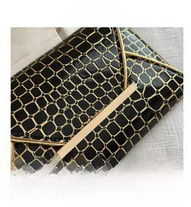 Makroansicht der schwarzen Leder-Clutch mit goldener Krokodilprägung und Metallverschluss