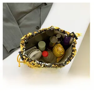 Spacious interior of a sequined drawstring bucket bag holding a fan and umbrella