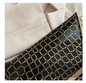 Detail der schwarzen Envelope-Tasche mit goldfarben geprägtem Steinmuster