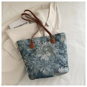 Close-up of floral tapestry fabric and leather handles on a large tote bag
