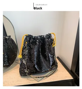Detail of black sequined bucket bag featuring yellow drawstring and chain strap