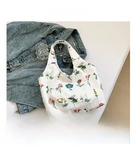 Floral print canvas tote bag displayed on blue denim jacket with aesthetic glassware