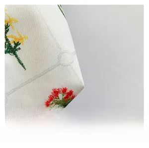 Macro shot of high-density floral embroidery on beige fabric with subtle grid pattern