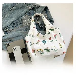 Detail showing white canvas tote bag with floral print and daily essentials for scale