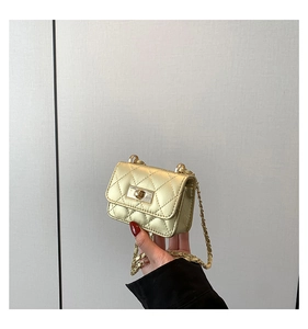 Macro detail of gold quilted mini bag featuring a square rotary lock and chain strap