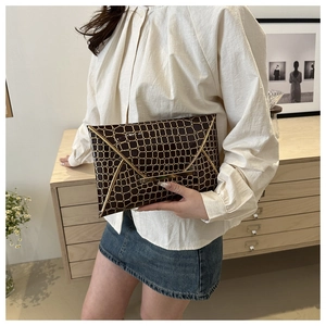 Details der dunkelbraunen Umschlag-Clutch mit Krokoprägung und elegantem Goldrand
