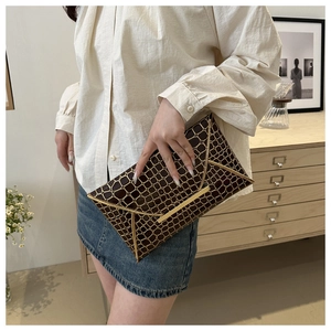 Nahaufnahme der dunkelbraunen Briefumschlag-Clutch mit Goldgittermuster und Metallkante