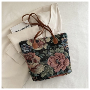 Detailed shot of floral jacquard tote bag with leather handles on a cream blazer