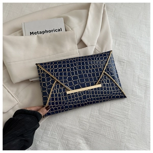 Detailansicht der dunkelblauen Umschlag-Clutch mit goldener Krokoprägung und Metallrand