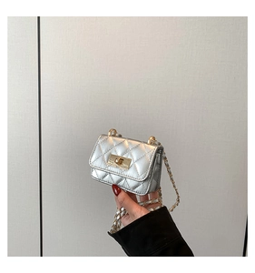 Close-up of quilted diamond pattern and gold-tone twist lock on silver crossbody bag