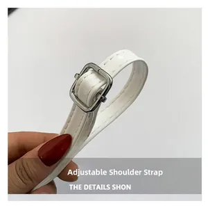 Close-up of adjustable white patent leather shoulder strap with silver buckle detail