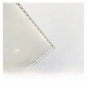 Detail shot of white glossy finish handbag edge with precise stitching and mirror texture