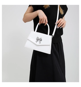 Close-up of white crossbody bag with silver butterfly buckle and smooth leather texture