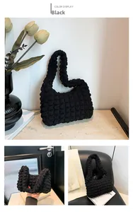 Détail de la texture gaufrée noire sur un sac à bandoulière chic en forme de croissant