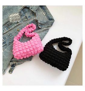Vue détaillée de sacs à bandoulière texturés à bulles rose et noir sur tissu denim