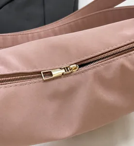 Dettaglio della cerniera dorata con tirante rettangolare su borsa in pelle rosa loto