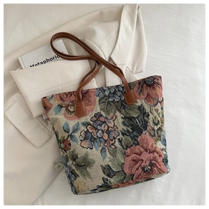 Close-up of floral tapestry tote bag with intricate jacquard weave and brown leather handles