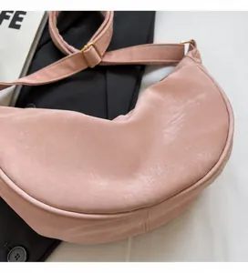 Dettaglio della borsa a mezzaluna in velluto rosa con trama morbida e fibbia dorata