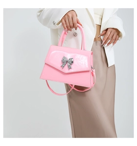Detailed view of pink patent leather handbag with a silver butterfly metal ornament