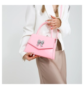 Close-up of a pink patent leather handbag featuring a silver butterfly buckle detail
