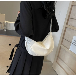 Dettaglio di una borsa a sella a mezzaluna in morbida pelle PU bianca con tracolla larga