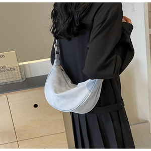 Dettaglio della borsa a mezzaluna in camoscio azzurro indossata con design minimalista