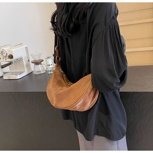 Borsa a tracolla a mezzaluna in pelle marrone vintage indossata da una modella