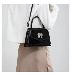 Detail of glossy black patent leather handbag with a silver rhinestone butterfly