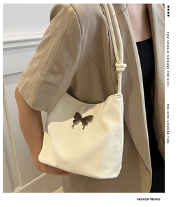 Détail du sac à bandoulière blanc crème avec papillon en métal et bandoulière nouée
