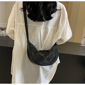Dettaglio di una borsa a mezzaluna in morbida pelle PU nera portata a spalla