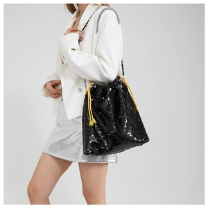 Chic black sequin drawstring bucket bag with metallic chain strap worn by model