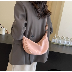 Dettaglio di una borsa a mezzaluna in velluto rosa con tracolla regolabile e sfondo curato
