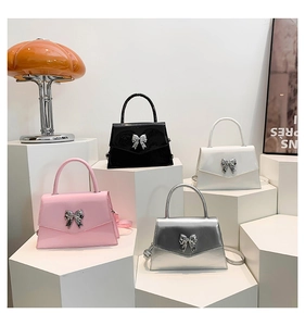 Detailed display of glossy patent leather handbags in pink, black, white, and silver tones