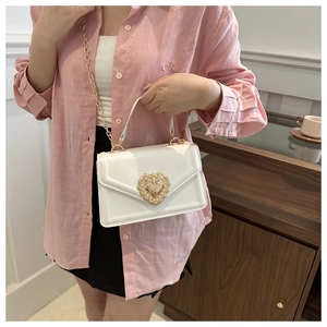 Détail d'un sac en cuir blanc avec fermoir cœur en perles et bandoulière dorée