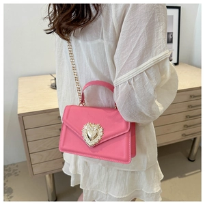 Détail du sac bandoulière rose vif avec fermoir en forme de cœur doré et perles