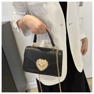 Détail du sac à bandoulière en cuir noir avec fermoir cœur baroque doré et ornements perles