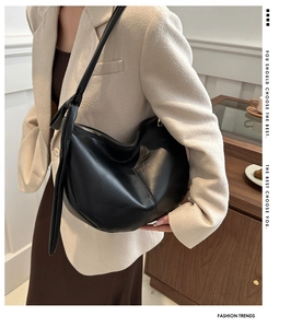 Chic black large capacity saddle bag with side knot detail worn by a model in a suit