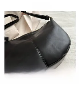 Detail of black PU leather saddle bag featuring metal zipper and vertical stitching