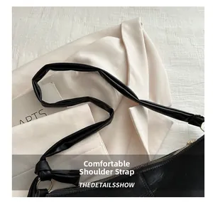 Close-up of black leather tote bag featuring a comfortable wide knotted shoulder strap