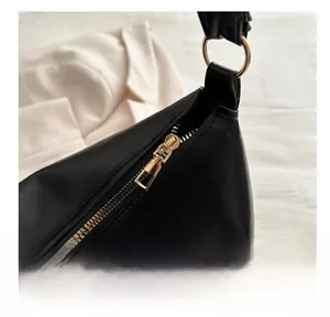 Close-up of smooth gold metal zipper and matte black PU leather on women's shoulder bag