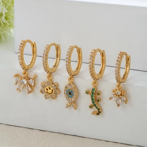 Détail de boucles d'oreilles créoles dorées 18k avec breloques en zircone