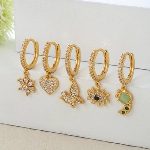 Detailliertes Set aus fünf goldenen Creolen mit Stern-, Herz-, Schmetterling- und Augen-Anhängern
