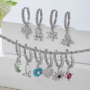 Klassische silberne Kupferohrringe mit Zirkon-Anhängern auf weißem Display-Treppen