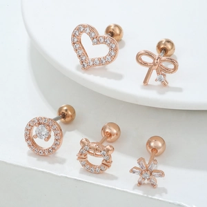 Vue macro de cinq clous d'oreilles en zircon rose doré aux motifs cœur et papillon