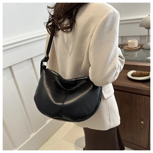 Detail of a large black crescent saddle bag in soft PU leather with metal zipper closure